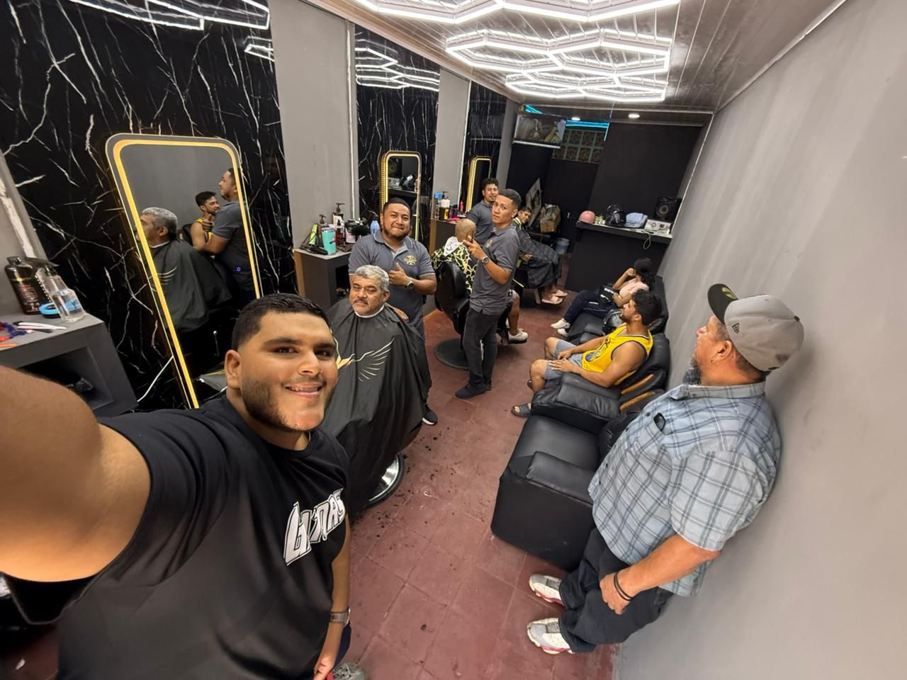 Interior de la barbería con clientes esperando