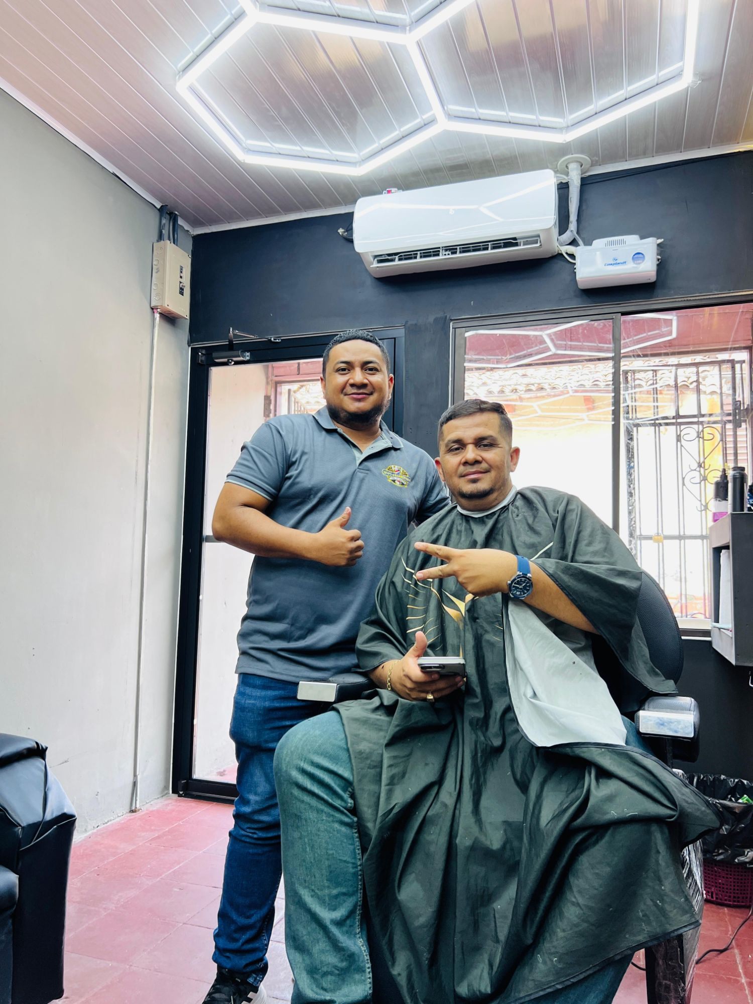 Tico junto a un cliente en la barbería